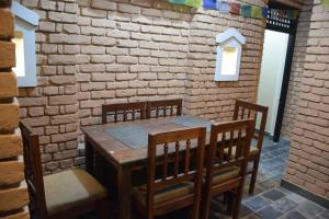 a wooden table and chairs in a room with a brick wall at Hotel Garangja in Bandīpur