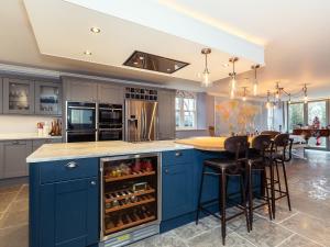 una cocina con armarios azules y una isla con bar en Vallis Oak Villa, en Frome