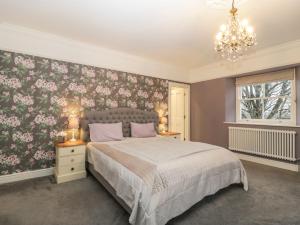 a bedroom with a large bed and a chandelier at Vallis Oak Villa in Frome