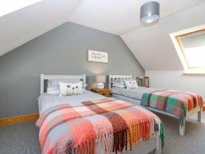 a attic bedroom with two beds and a window at Stable Cottage in Inverurie