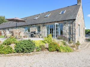 a stone house with a table and an umbrella at Stable Cottage in Inverurie