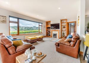 a living room with leather furniture and a large window at Cascade in Saundersfoot