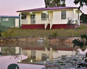 a house with a reflection in a body of water at RIVER DOWNS COTTAGE in Clarence Town