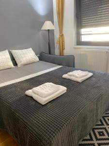 Una cama con dos toallas blancas encima. en Family Home Niš, en Niš