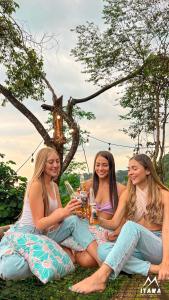 Glamping Itawa & Ecoparque turístico في فيلافيسينسيو: ثلاث نساء يجلسن حول طاولة مع أكواب من النبيذ