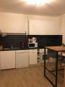 a kitchen with white cabinets and a table and a microwave at Appartement Lille Europe in Lille