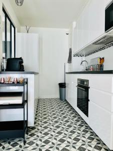 uma cozinha com piso em azulejo preto e branco em Appartement cocooning em Villetaneuse