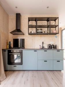 a kitchen with white cabinets and a stove at Ultiem ontspannen in compleet ingericht tiny house in bosrijke omgeving in Nunspeet