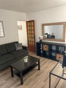 uma sala de estar com um sofá, uma mesa e um espelho em La mission em Saint-Martin-des-Noyers