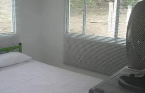 1 dormitorio con 1 cama y ventana con ventilador en Cabañas El Paraiso, en La Mesa
