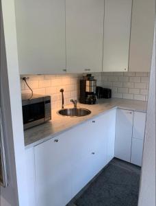 a white kitchen with a sink and a microwave at Glöm dina bekymmer i denna rymliga lägenhet in Trollhättan