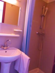 a bathroom with a sink and a shower with a mirror at Hôtel Duchesse Anne in Lourdes