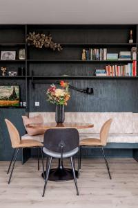 een eetkamer met een tafel en stoelen met een vaas met bloemen bij Ultiem ontspannen in compleet ingericht tiny house in bosrijke omgeving in Nunspeet