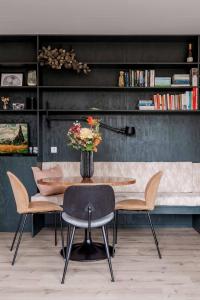 a dining room with a table and chairs with a vase of flowers at Ultiem ontspannen in compleet ingericht tiny house in bosrijke omgeving in Nunspeet