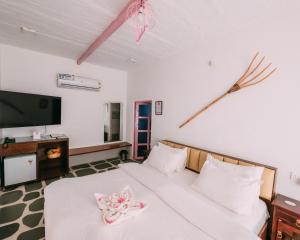 Schlafzimmer mit einem Bett mit weißer Bettwäsche und einem Flachbild-TV in der Unterkunft The Luxe Pushkar By Namli Hotels in Pushkar