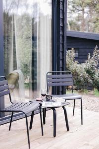 twee stoelen en een tafel met een glas wijn bij Ultiem ontspannen in compleet ingericht tiny house in bosrijke omgeving in Nunspeet