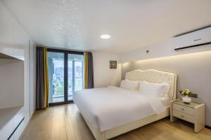 a white bedroom with a large bed and a window at Xinghe Times Apartment - Shenzhen North Railway Station in Shenzhen