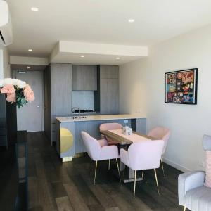 una cocina con mesa y algunas sillas rosas en Sky Apartment - Realm Adelaide en Adelaida