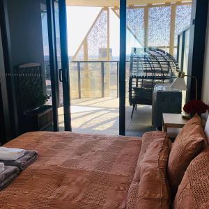 1 dormitorio con 1 cama grande y vistas a un balcón en Sky Apartment - Realm Adelaide en Adelaida