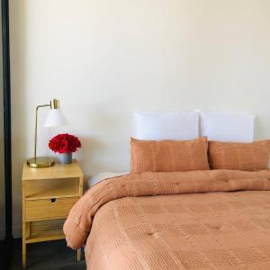 a bed with an orange blanket and a table with a lamp at Sky Apartment - Realm Adelaide in Adelaide