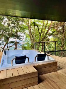 比亞維森西奧的住宿－Itawa Luxury Glamping & Ecoparque turísticos，甲板上的浴缸,配有两把椅子