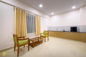 Habitación con 2 sillas, mesa y TV. en Daffodils Luxury Airport Suites, en Angamaly