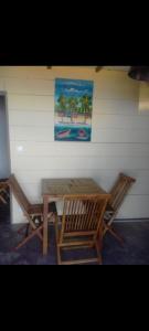 a picnic table and two chairs next to a wall at T2 vue sur Ocean Indien in Saint-Leu