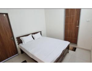 um pequeno quarto com uma cama com lençóis brancos em Hotel Roopmati, Vidisha em Vidisha