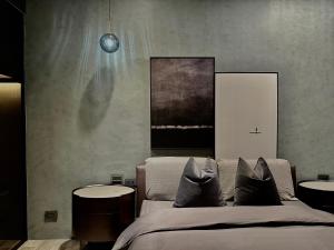 a bedroom with a bed with two tables and a painting at HERE宅這兒私宅-屏市宅 in Pingtung City