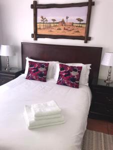 a bedroom with a white bed with a picture on the wall at Alendo Apartments in Johannesburg