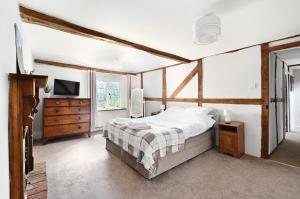 a bedroom with a bed and a dresser and a tv at Walnut Tree House in Rustington