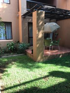 un patio con mesa y sombrilla en Alendo Apartments en Johannesburgo
