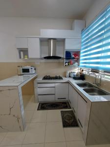 uma cozinha com armários brancos, um lavatório e uma janela em M2H Homestay em Kuantan