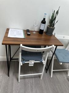 a wooden desk with a bottle of wine and a chair at New Cozy Studio Apt. House with Parking. Entire space in Slades Green