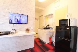 a kitchen with a black refrigerator and a tv on the wall at Ozawa Building in Osaka