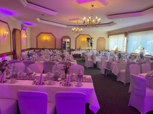 einen Bankettsaal mit weißen Tischen und lila Stühlen in der Unterkunft Hotel Geromont in Andernach