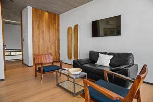 una sala de estar con un sofá de cuero negro y sillas en Casa Galería Blackaller, en La Paz