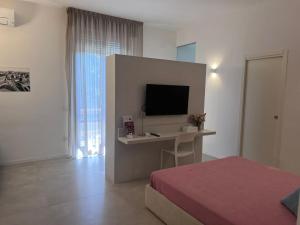 a bedroom with a bed and a desk with a television at B&B LE MAGNOLIE in Termoli