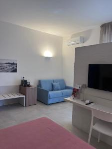 B&B LE MAGNOLIE في تيرمولي: غرفة معيشة مع أريكة زرقاء وتلفزيون