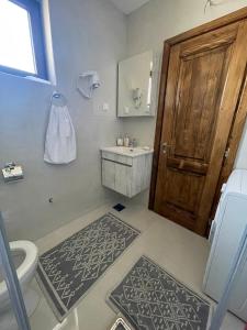 łazienka z toaletą, umywalką i drewnianymi drzwiami w obiekcie LUX VILA MOTICKI GAJ w mieście Žabljak