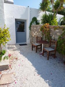 two benches and a table in front of a door at Eri Hotel in Parikia