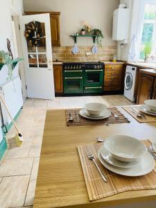 a kitchen with a table with plates on it at Large Home with 5 car Parking next to Train station, Airport, NEC in Marston Green