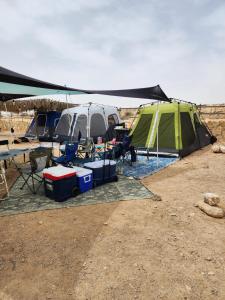a tent and a table and chairs in a field at חוות נועם במדבר - noam farm in Mitzpe Ramon