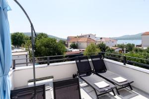 - deux chaises sur un balcon avec vue sur l'eau dans l'établissement Apartments Grape, à Pirovac