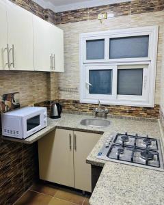 a kitchen with a stove and a microwave at شقه مفروش الترا سوبر لوكس مدينتى in Madinaty