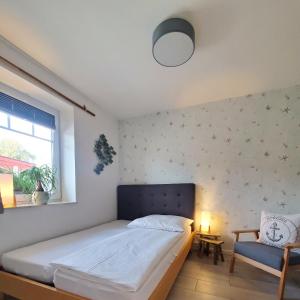 a bedroom with a bed and a chair and a window at NordseeLiebe - Zeit Für Meer in Bredstedt