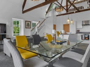 a dining room with a glass table and yellow chairs at Pass the Keys Yew Tree Stunning Apartment with Sea View in Grange Over Sands
