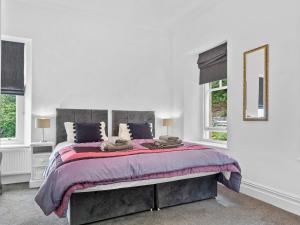 a white bedroom with a large bed and two windows at Pass the Keys Yew Tree Stunning Apartment with Sea View in Grange Over Sands