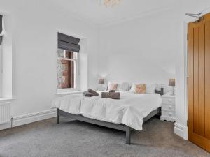 a white bedroom with a bed and a window at Pass the Keys Yew Tree Stunning Apartment with Sea View in Grange Over Sands