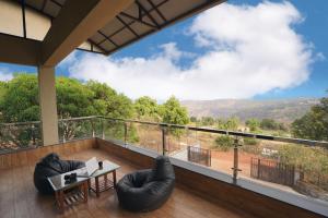 a room with a balcony with a table and chairs at Aksha Villa in Panchgani
